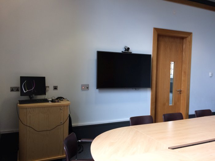 Flat floored meeting room with boardroom table and chairs and video monitor