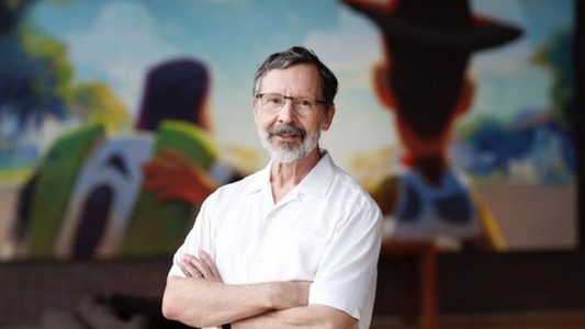 promo picture of Ed Catmul (an older white man with grey beard in a short white shirt) in front of a projection screen of Toy Story