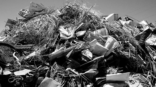 black and white photo of a metal scrap heap composed of bunched metal wire, car and home appliance pieces, baskets, fences etc