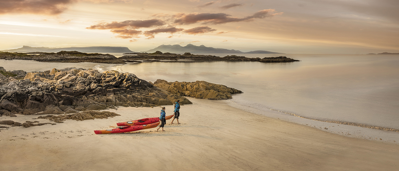 Two people with kayaks on Camusdarach beach