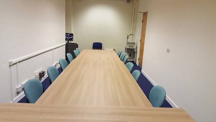 Flat floored meeting room with tables and chairs and a PC