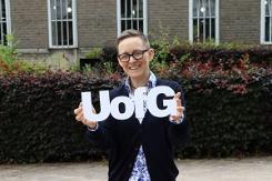 Photograph of Dr Amanda Sykes holding a UofG sign