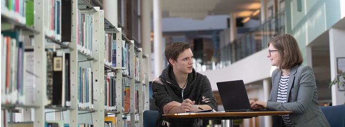 Students sitting at a table with a laptop in the library