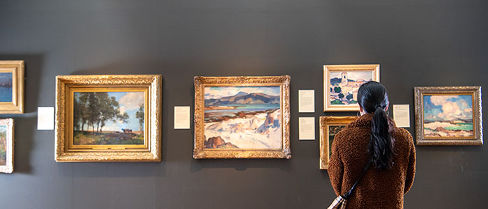 A woman looking at paintings in the Hunterian Art Gallery.