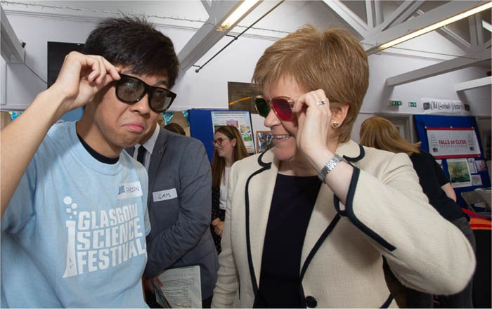 Photograph of a GSF volunteer with First Minister Nicola Sturgeon. Both of them are wearing coloured glasses.