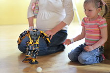 Photograph of a child with a small robot. 
