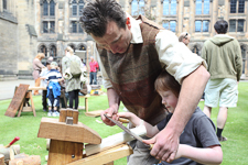Photograph showing an adult teaching a child carpentry skills. 