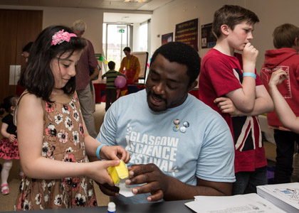 Photograph of a GSF volunteer showing a child how to make crystal models out of paper. 