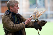 Photograph of a man with an owl on his arm. 