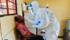 Image of a researcher in full PPE taking a swab from an African patient