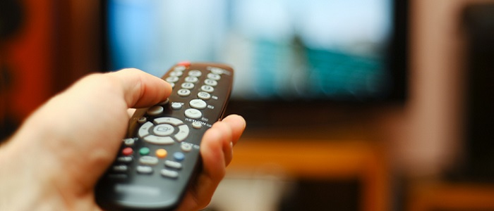 A person holding the remote in front of the TV