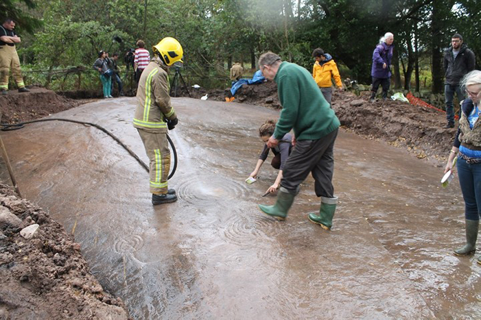 The Cochno Stone being cleaned by a local firefighter during the 2016 excavations.