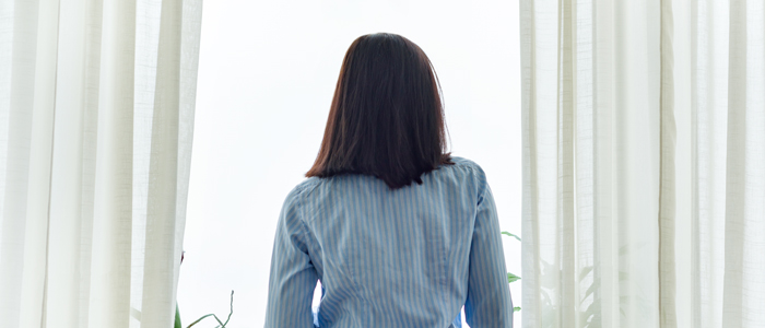 Photo of back view of woman standing at window