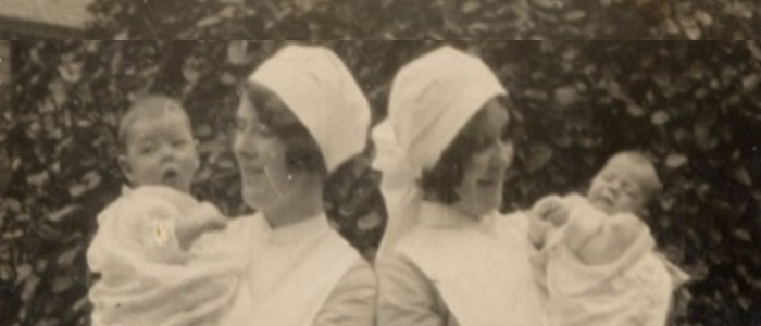 Two nurses in uniform holding infants recovering from pneumonia