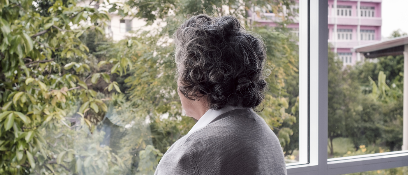Photo of a back view of a woman looking out of a window
