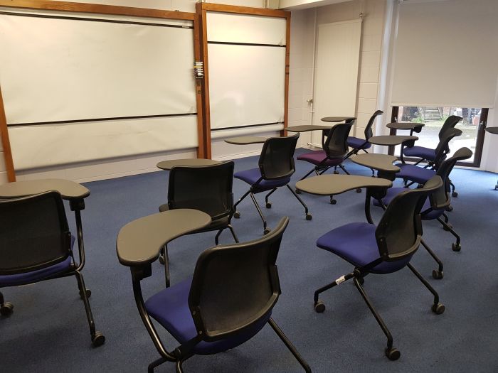 Flat floored teaching room with tables and chairs and whiteboards