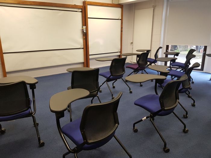 Flat floored teaching room with tablet chairs and whiteboards.