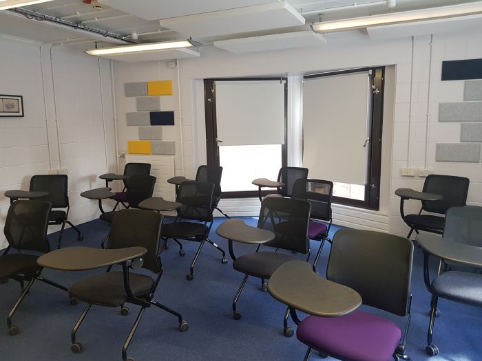 Flat floored teaching room with tablet chairs.