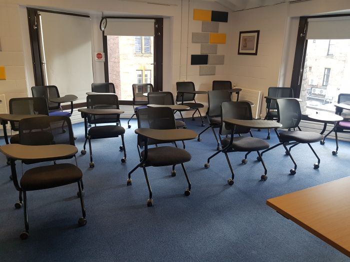 Flat floored teaching room with tablet chairs.