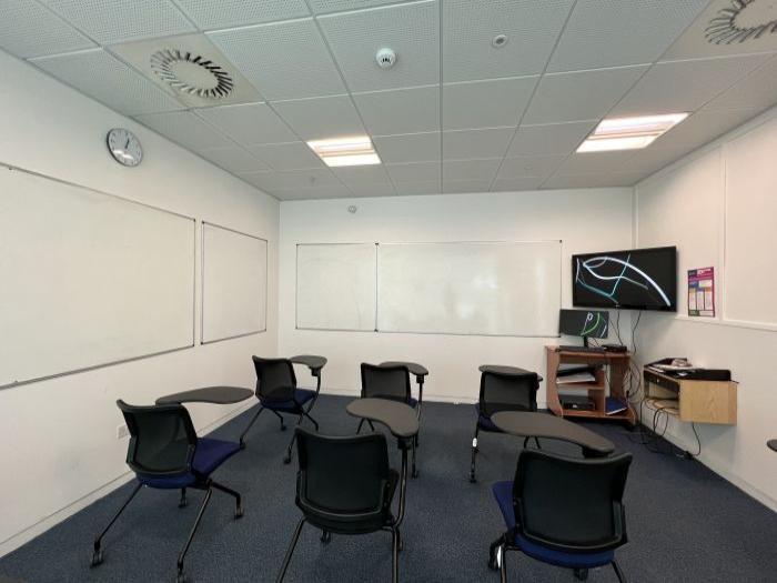 Flat floored teaching room with tablet chairs, whiteboards, visualiser, and PC.