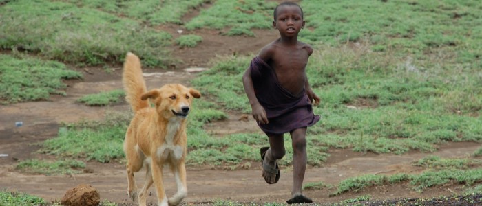 Boy running with dog in Tanzania