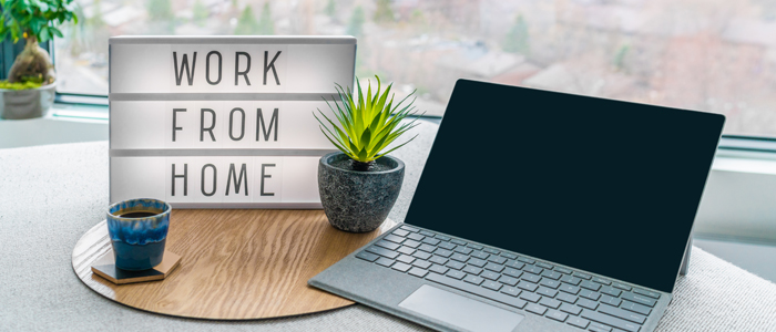 Laptop sat on a desk next to a lightbox spelling out 'Working from home'
