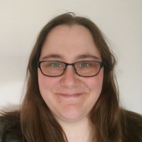 Head of woman, smiling, with glasses, brown hair, green eyes