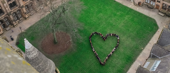 Photo from above of students forming a heart shape on the grass in the Quad