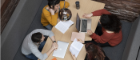 A group of students sitting together in a study pod with laptops and books