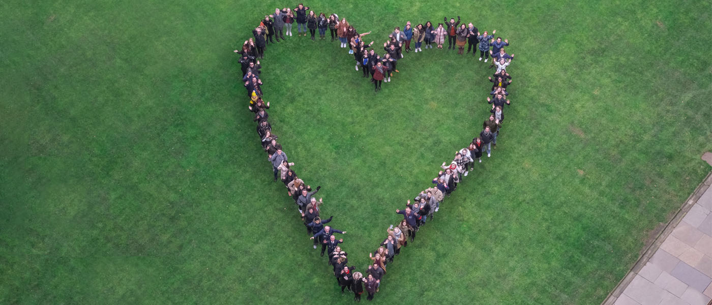Staff and students stand in the Quadrangles in the shape of a heart