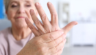 An older woman holding her left hand in her right hand up to the camera