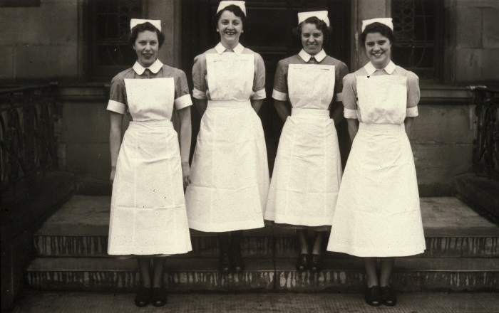 Four nurses in uniform on steps