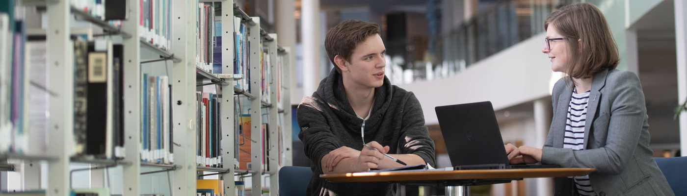Two students talking in the library