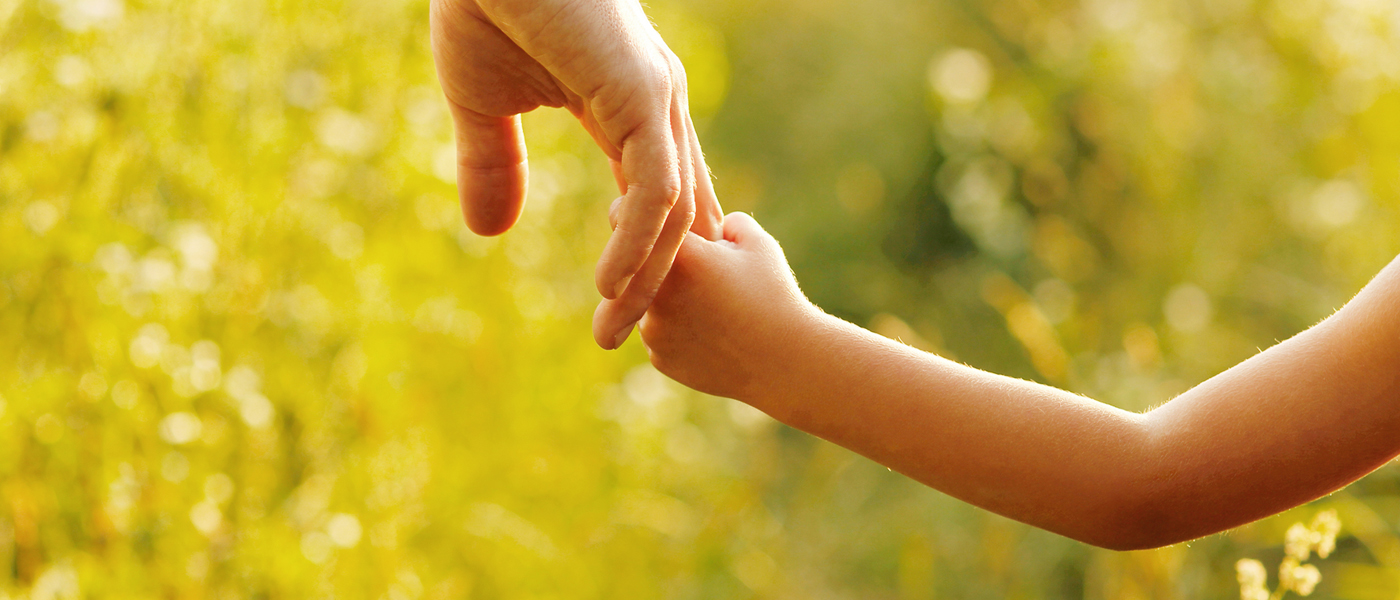 Father holding child's hand outdoors