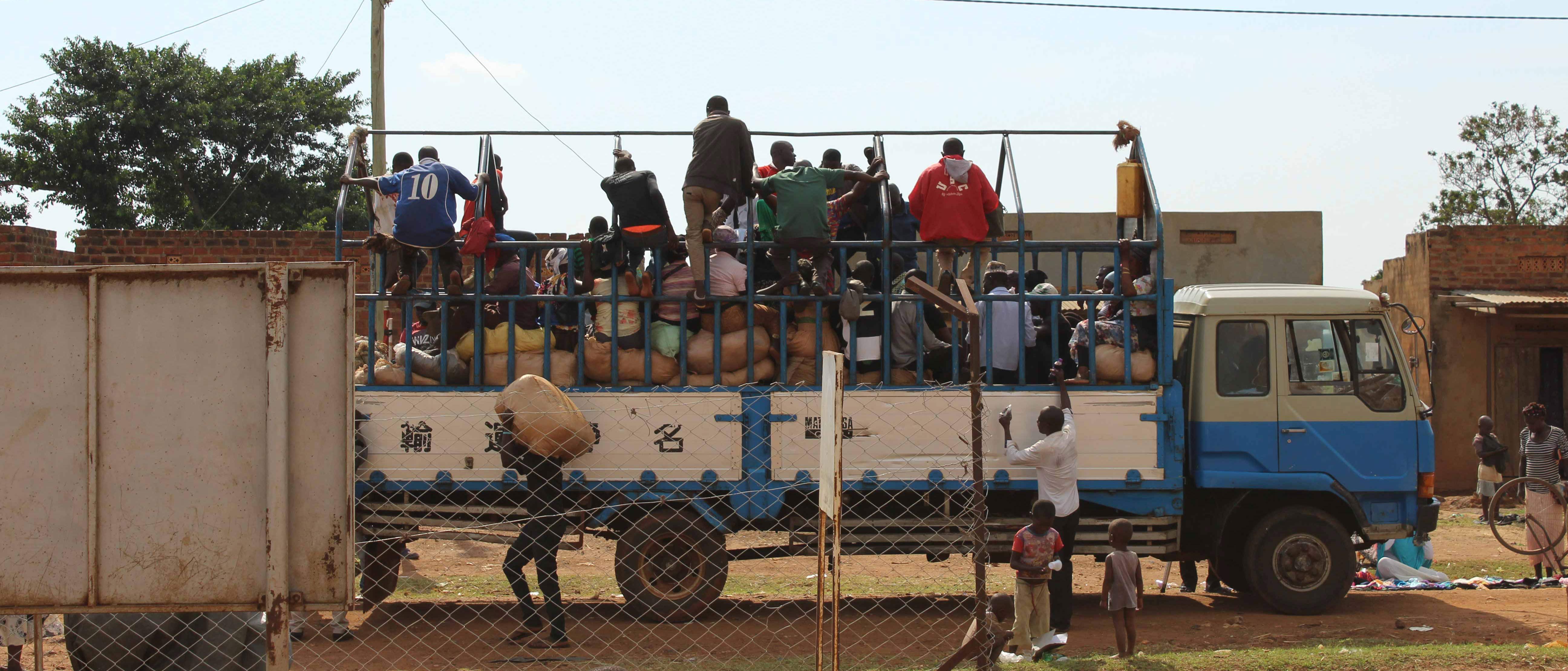 Large truck on a dirt road, packed with people and bags of goods