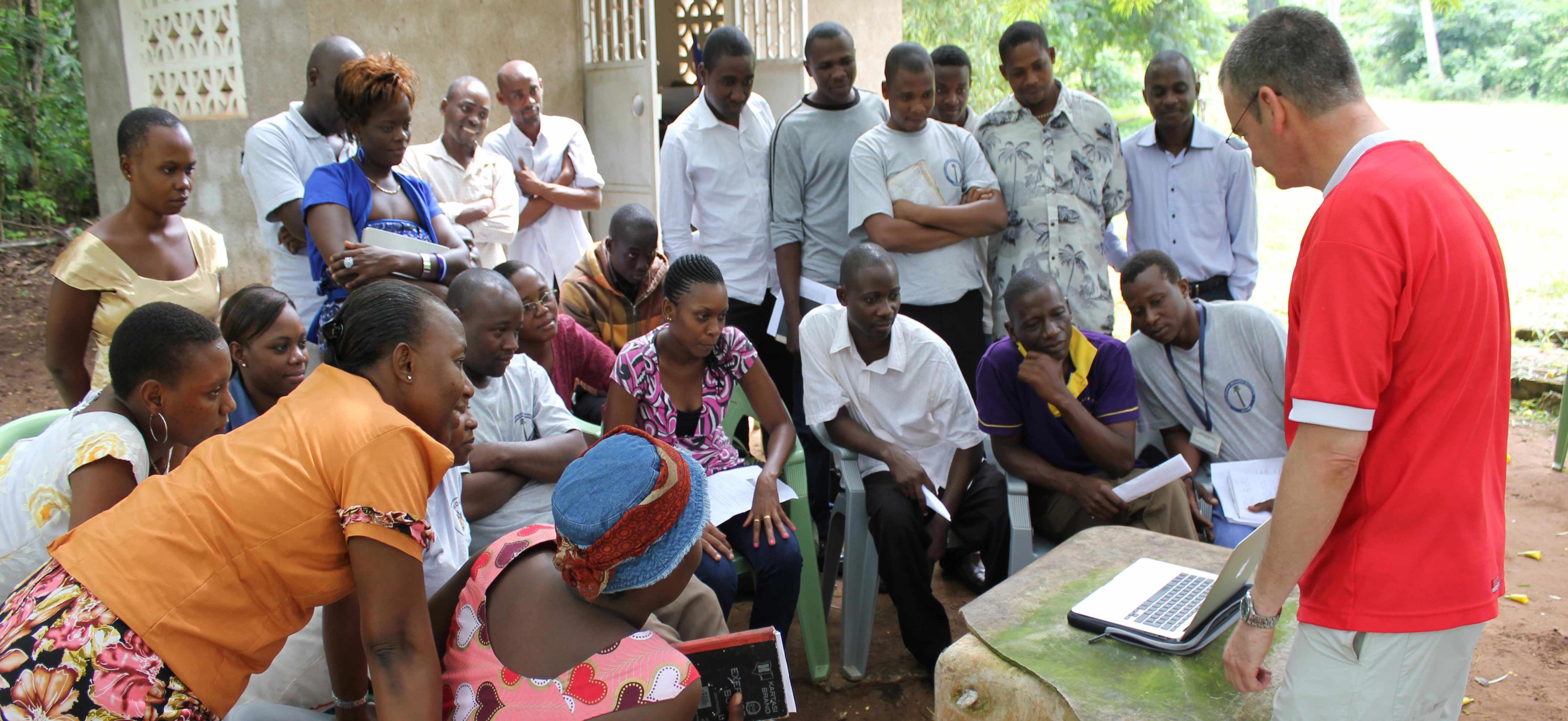 Outdoor classroom with group of people looking at a laptop 