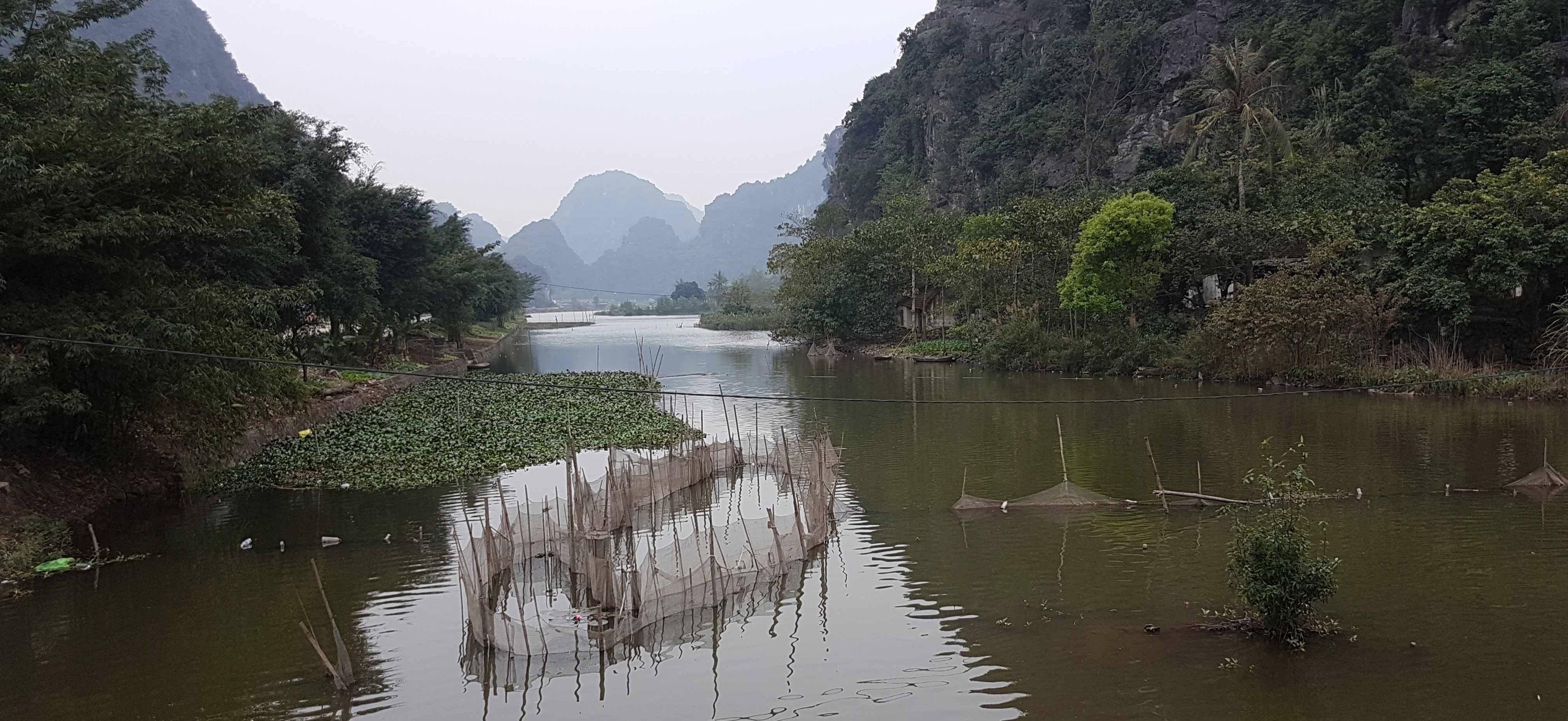 Fish pens in a canal surrounded by steeps hills in northern Vietnam