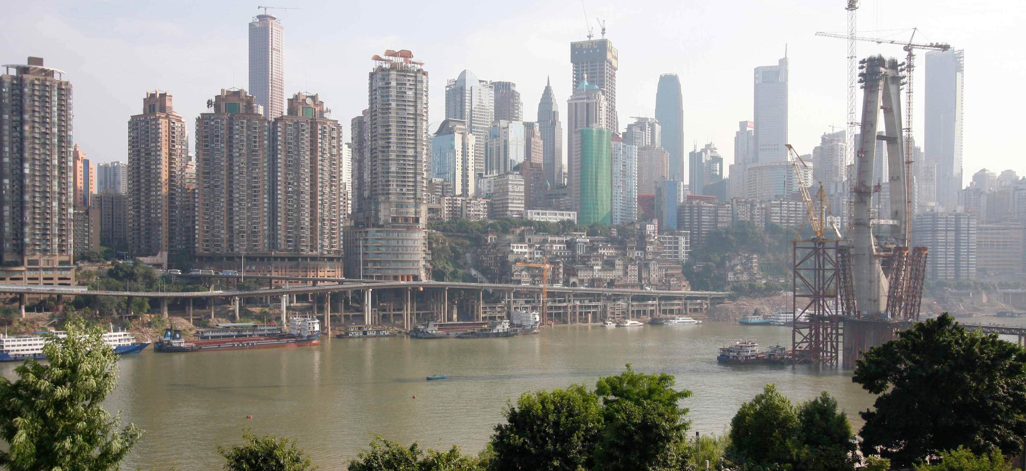 High-rise buildings, many under construction, along a river in Chongqing, China