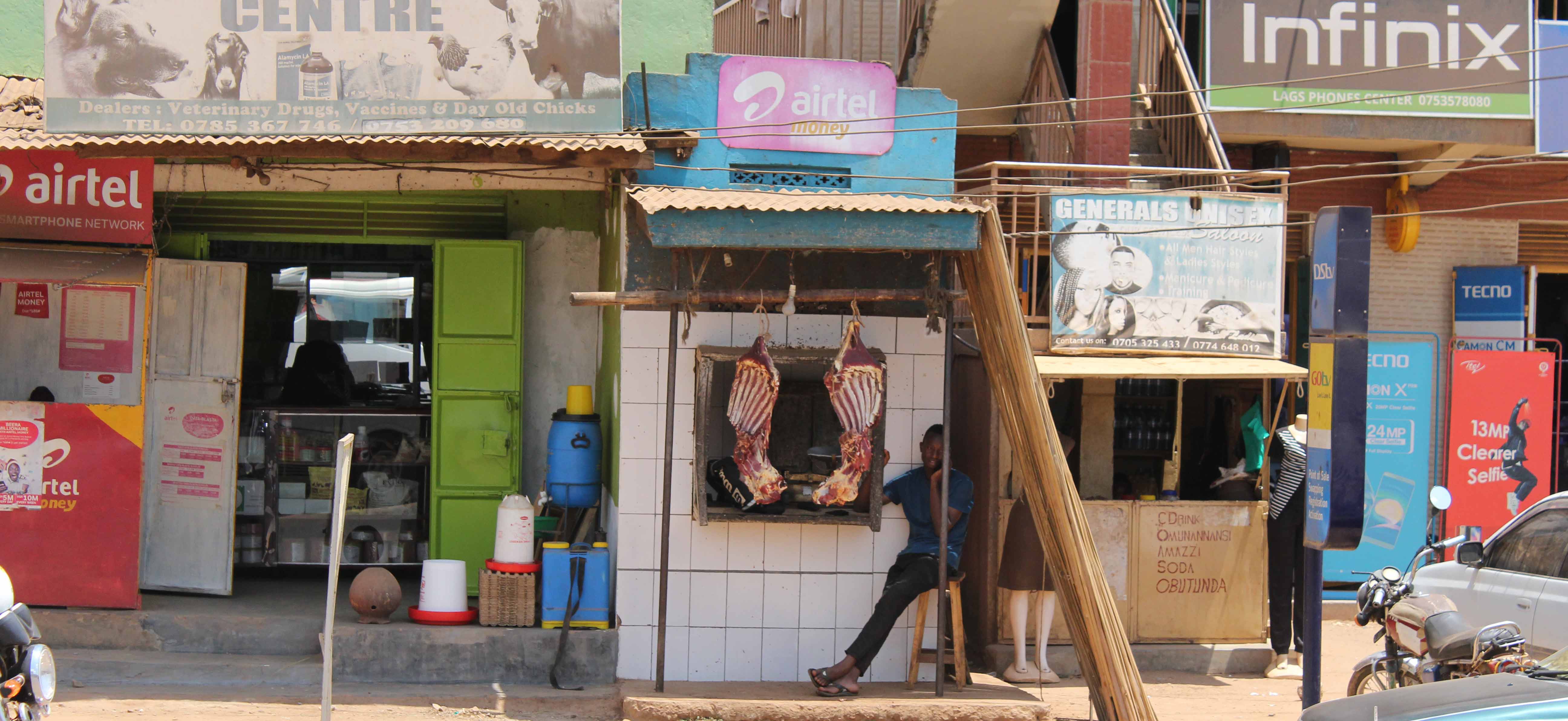 Entrances to several shops, including a butcher with meat hanging outside, in Uganda
