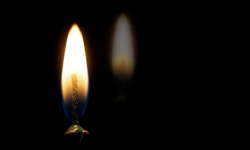 Black image with candle flame and reflection