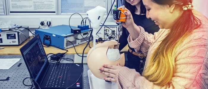 Two people use a surgical practice dummy to test a new skull drill