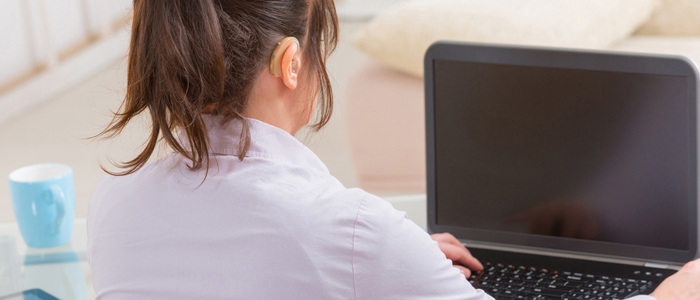 Photo of woman wearing hearing aid working on laptop