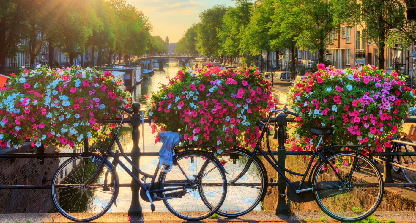 Vibrant flowers and bicycles on a bridge overlooking a canal in Amsterdam [Photo: Shutterstock]