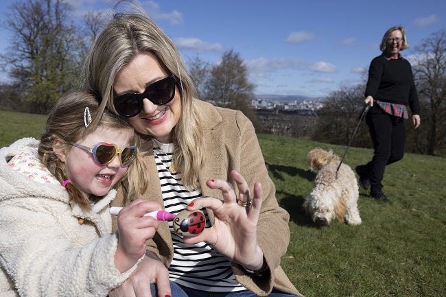 Emma Gilmartin and daughter Millie (age 4) from Glasgow sitting in the park as Rafa the dog is being walked by  Professor Deirdre Heddon of the University of Glasgow who is leading the Covid Walking Project. Photo credit Martin Shields