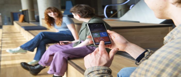 Stydent holding phone with safezone app showing