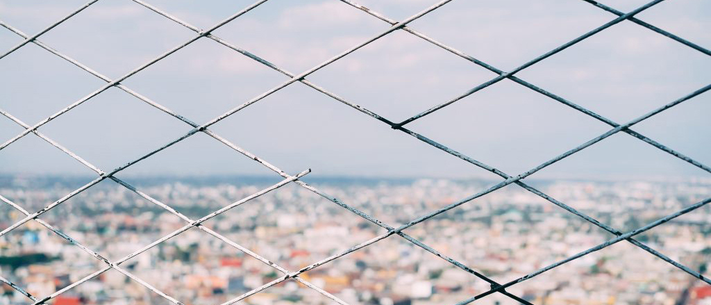 City viewed through a chain link fence