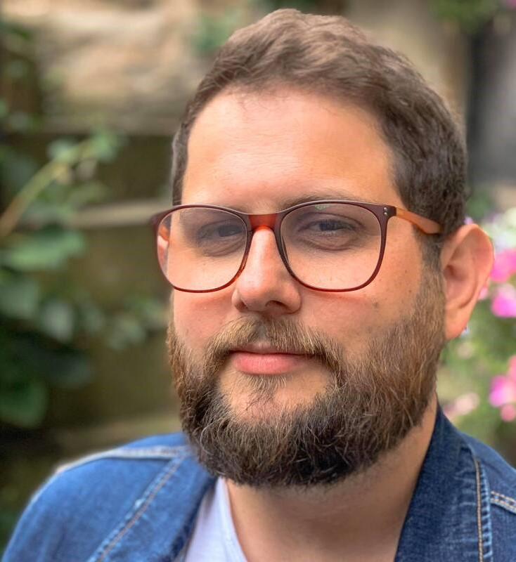 A head and shoulders shot of Matthew Sinton outdoors with flowers in the background