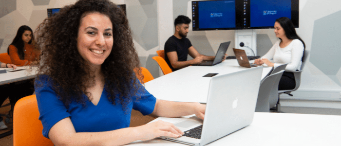 Image of a person smiling, sitting at a laptop
