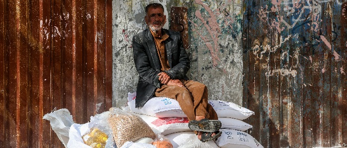 Man sitting in shared on a pile of donated food