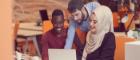 Photo of three BAME young people at a laptop